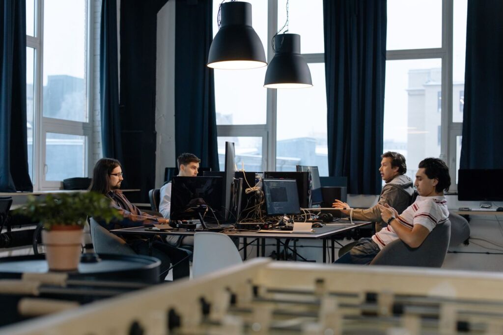 Workers collaborate in a modern office with computers, showcasing teamwork in technology development.